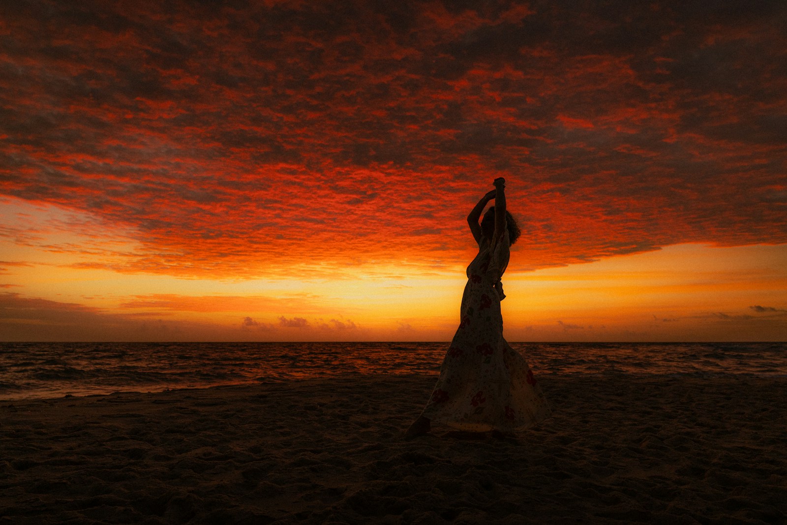 Photo by Alef Morais Silhouette of a woman dancing on a beach at sunset.