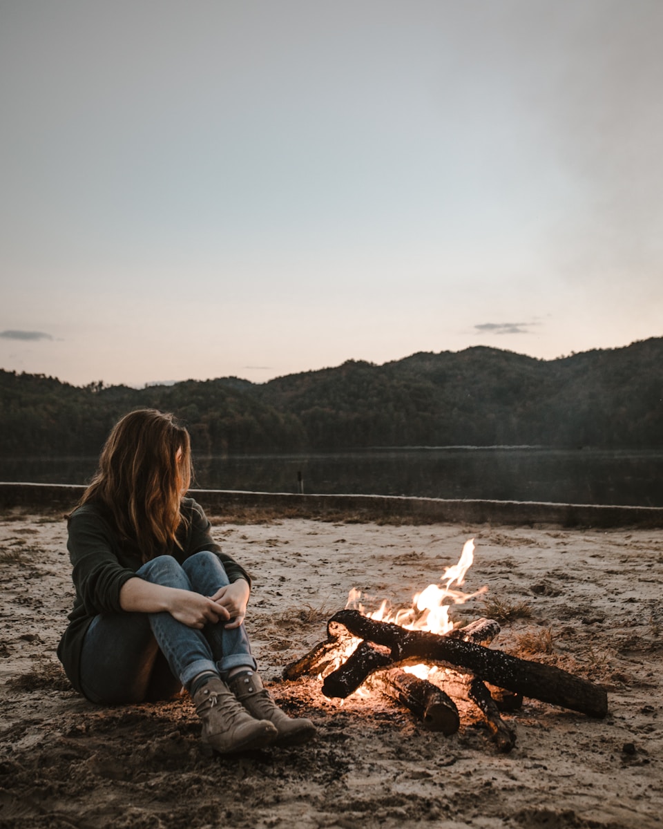Photo by Zach Camp a woman sitting in front of a campfire